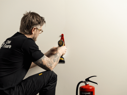 Clas Fixares hantverkare hjälper till med att montera upp brandsläckare för ett säkert hem