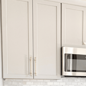 Skåpluckor med moderna handtag hänger ovanför en mikrovågsugn i ett ljust kök. Clas Fixares snickartjänster kan hjälpa till med installation och justering för en mer funktionell köksmiljö.