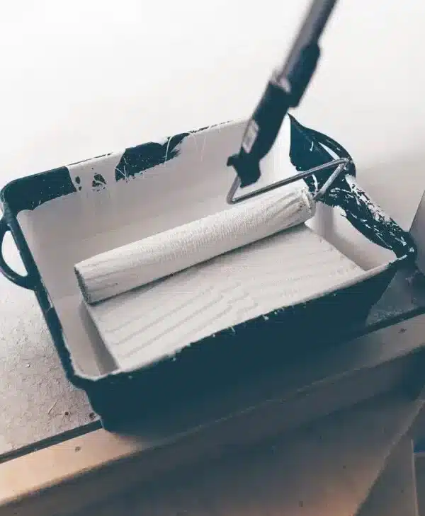 Färgrulle täcks med vit färg i en plastbricka. Passar perfekt för Clas Fixares målningstjänster där skickliga hantverkare erbjuder hjälp med renoveringar och förbättringar i hemmet.